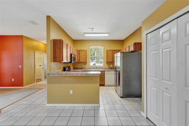 kitchen with light tile patterned flooring, appliances with stainless steel finishes, a textured ceiling, and sink