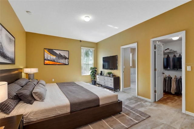 bedroom featuring ensuite bathroom, a walk in closet, light carpet, and a closet