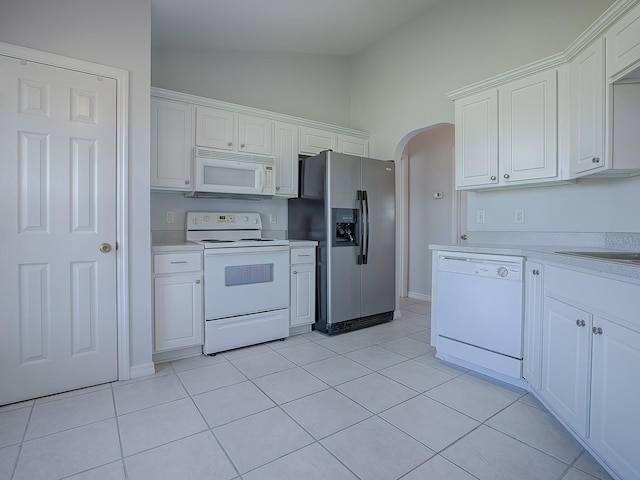 kitchen with white cabinetry, white appliances, lofted ceiling, and light tile patterned floors