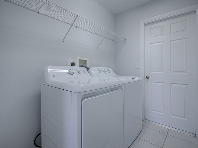 clothes washing area featuring light tile patterned floors and washer and clothes dryer