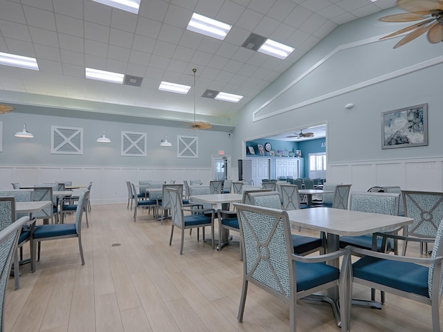 dining area with a towering ceiling, ceiling fan, and light wood-type flooring