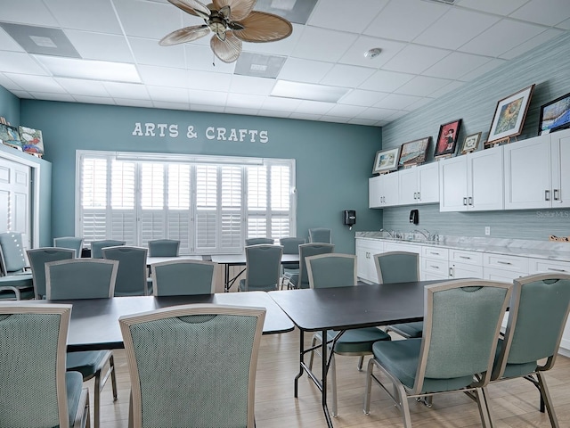 dining area with ceiling fan, a paneled ceiling, a healthy amount of sunlight, and light hardwood / wood-style flooring