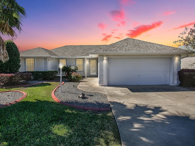 single story home featuring a garage and a yard