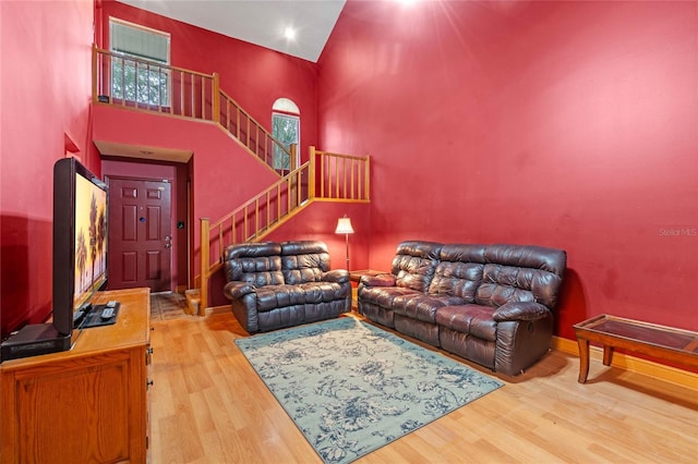 living room with wood-type flooring and a towering ceiling