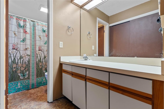 bathroom featuring a skylight, a shower with curtain, vanity, and toilet