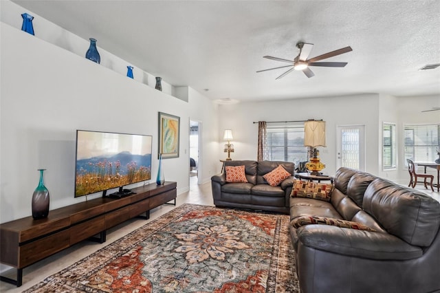 living room with ceiling fan and a textured ceiling