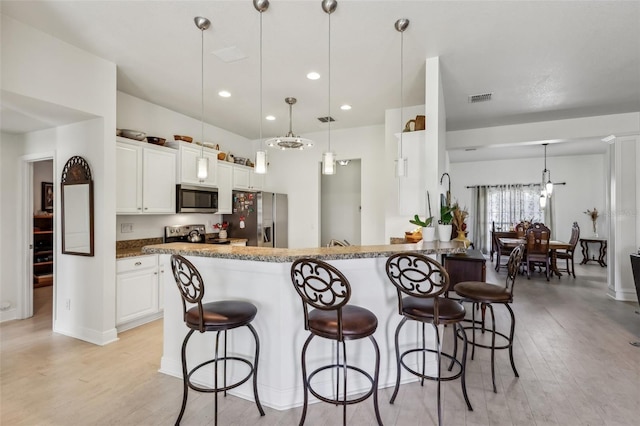 kitchen with white cabinets, stainless steel appliances, kitchen peninsula, and stone countertops