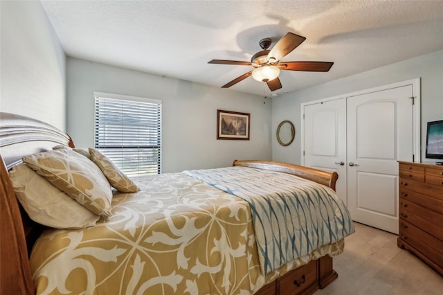 bedroom with a textured ceiling, a closet, light hardwood / wood-style flooring, and ceiling fan