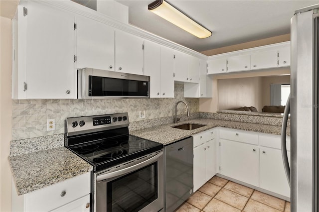 kitchen featuring appliances with stainless steel finishes, light stone counters, white cabinetry, and sink