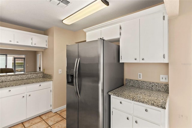 kitchen featuring white cabinets, light stone countertops, stainless steel fridge with ice dispenser, and light tile patterned floors