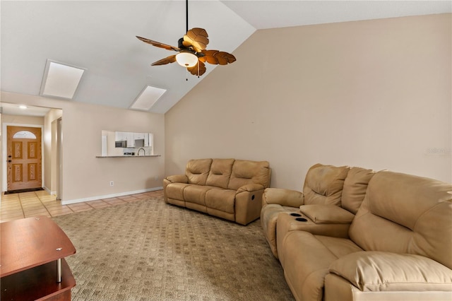 tiled living room featuring ceiling fan and vaulted ceiling with skylight