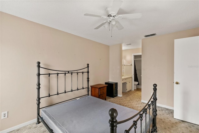 bedroom featuring connected bathroom, ceiling fan, light colored carpet, and a textured ceiling