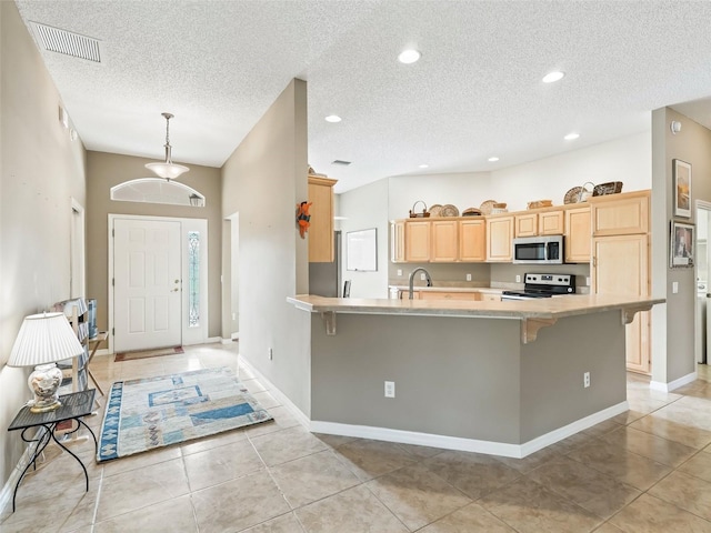 kitchen featuring a kitchen breakfast bar, kitchen peninsula, light brown cabinetry, and appliances with stainless steel finishes