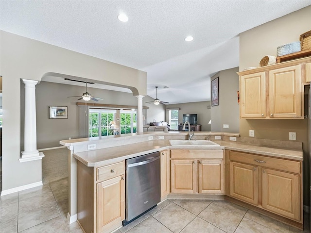 kitchen featuring kitchen peninsula, decorative columns, stainless steel dishwasher, a textured ceiling, and sink