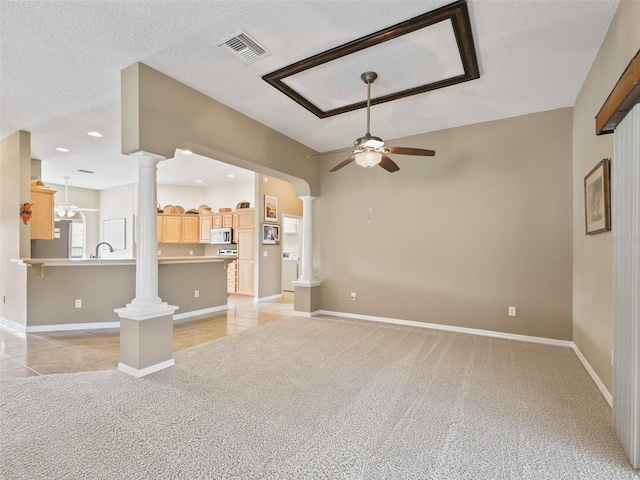 unfurnished living room featuring light carpet, a textured ceiling, decorative columns, and ceiling fan