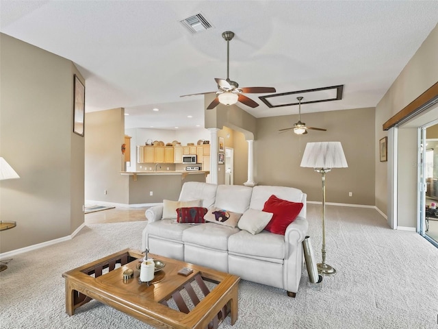 living room featuring decorative columns, light carpet, sink, and ceiling fan