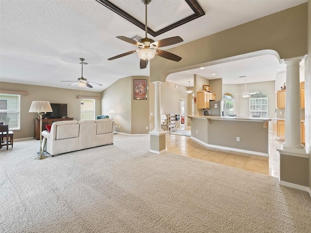 carpeted living room with vaulted ceiling, a wealth of natural light, ceiling fan, and a textured ceiling