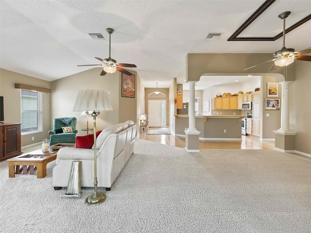 carpeted living room featuring ornate columns, lofted ceiling, ceiling fan, and a textured ceiling