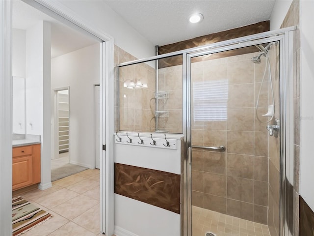 bathroom with tile patterned flooring, vanity, a shower with shower door, and a textured ceiling