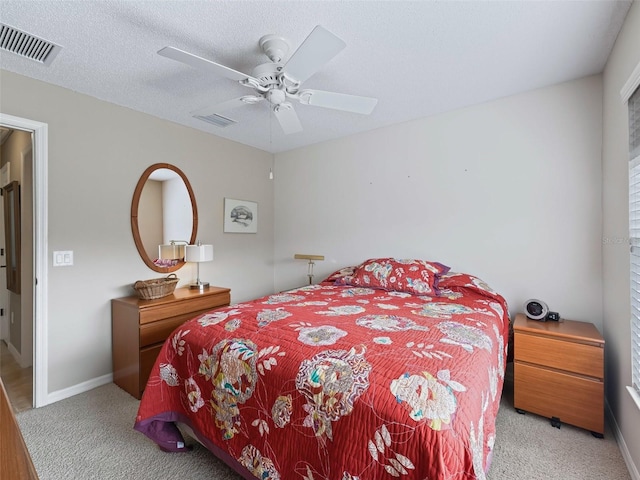 bedroom featuring ceiling fan, light carpet, and a textured ceiling