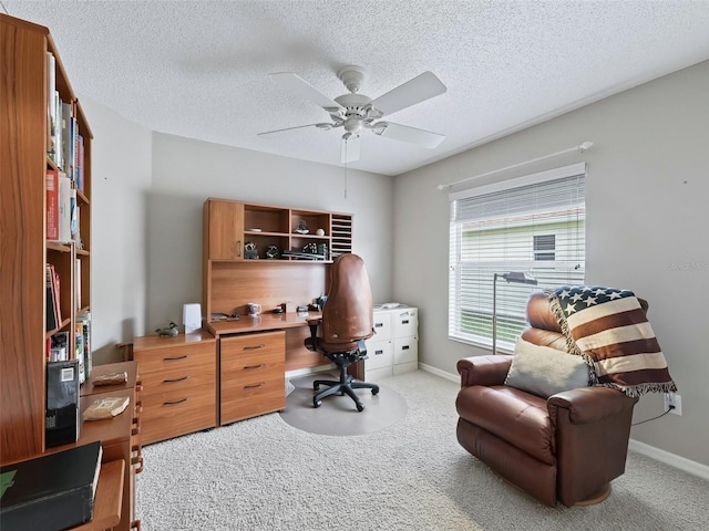 carpeted home office with ceiling fan and a textured ceiling