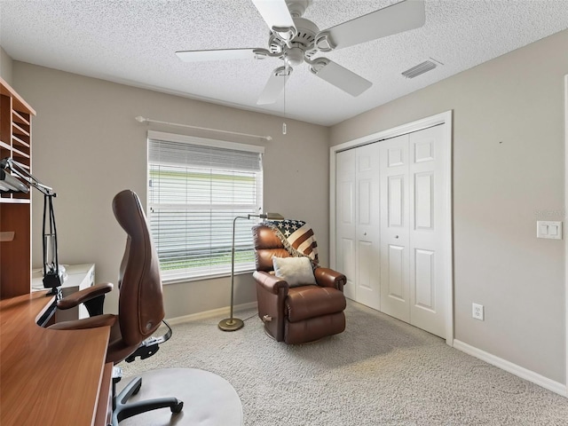 carpeted office space with ceiling fan and a textured ceiling