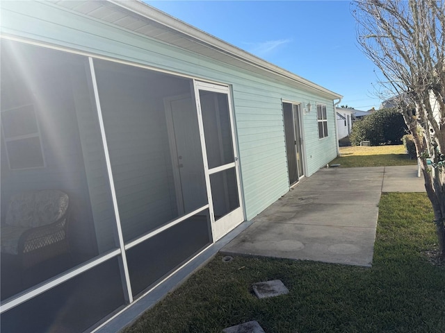 view of side of home featuring a patio and a lawn