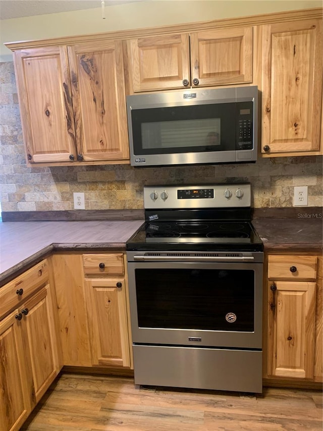 kitchen with tasteful backsplash, light hardwood / wood-style flooring, and appliances with stainless steel finishes