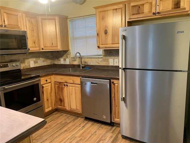 kitchen featuring sink, backsplash, stainless steel appliances, and light wood-type flooring