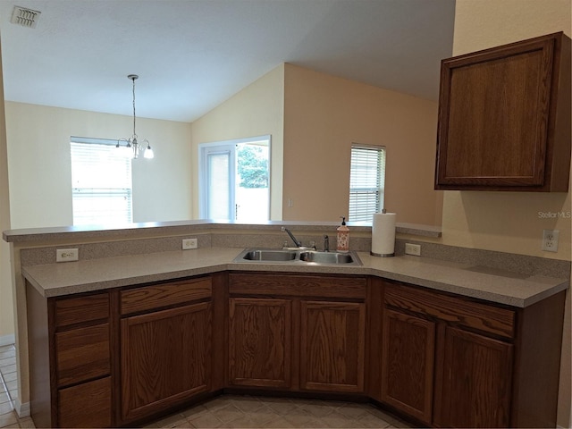 kitchen with kitchen peninsula, vaulted ceiling, a notable chandelier, and sink