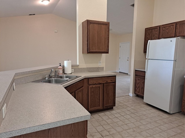 kitchen with kitchen peninsula, white refrigerator, lofted ceiling, and sink