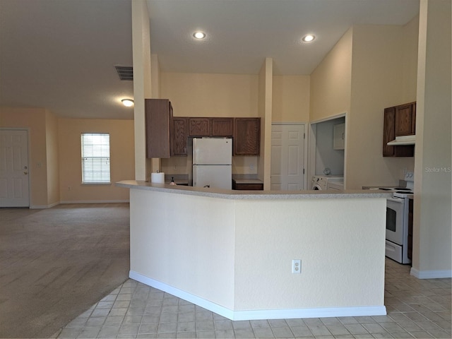 kitchen featuring light carpet, white appliances, and separate washer and dryer