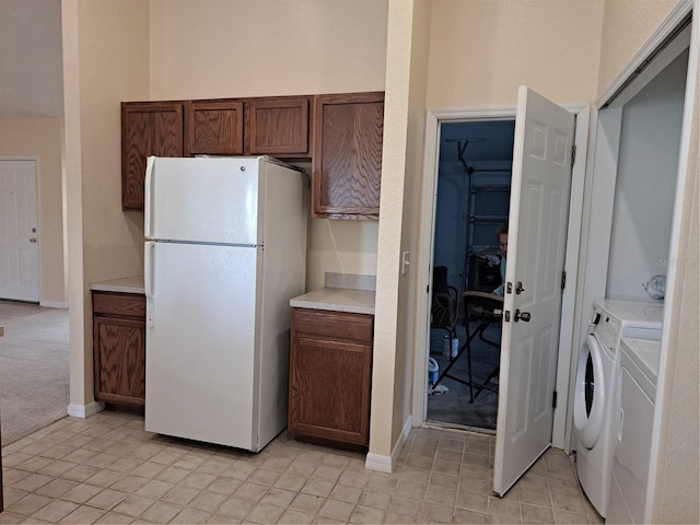 kitchen with washing machine and dryer, light carpet, and white fridge