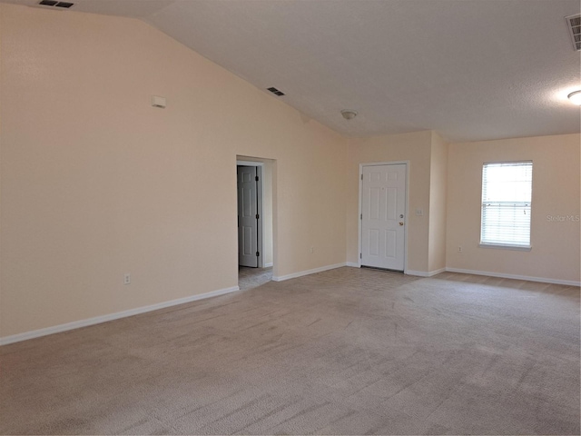 unfurnished room featuring light colored carpet and vaulted ceiling