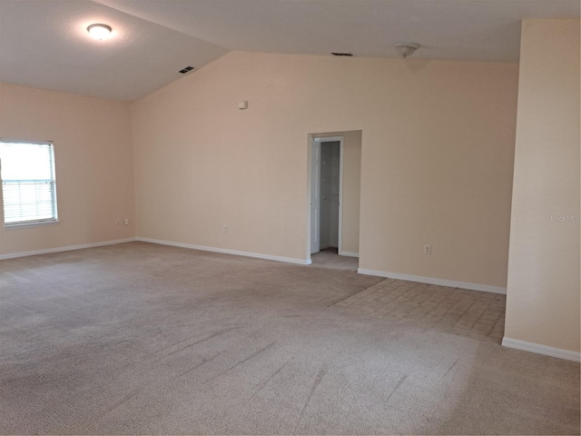 carpeted empty room featuring vaulted ceiling