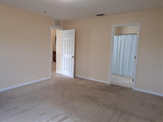 unfurnished room with light colored carpet and a textured ceiling