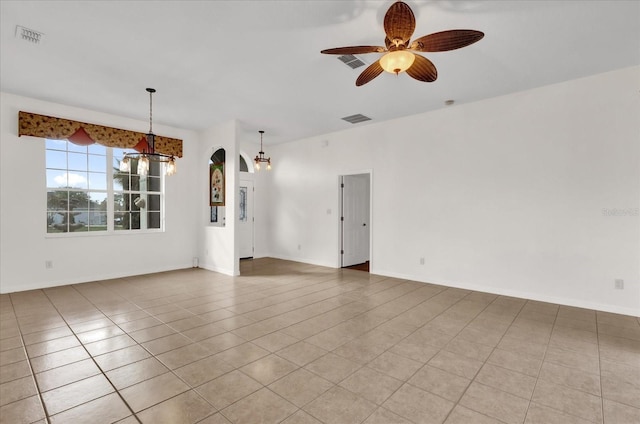 tiled spare room with ceiling fan with notable chandelier