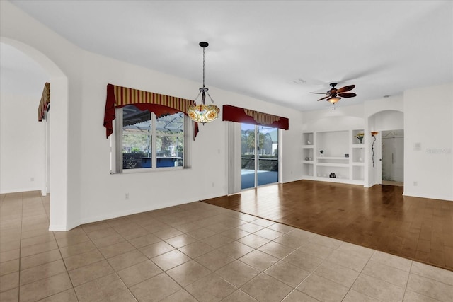 interior space featuring light tile patterned floors, ceiling fan, and built in shelves