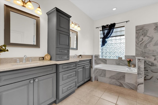 bathroom with a relaxing tiled tub, vanity, and tile patterned flooring