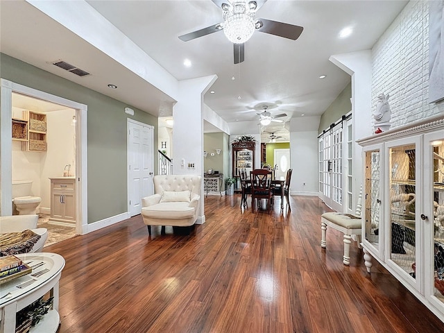 interior space featuring ceiling fan, a barn door, and dark hardwood / wood-style floors