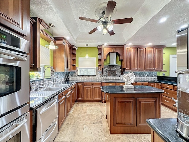 kitchen featuring a center island, wall chimney exhaust hood, a raised ceiling, hanging light fixtures, and tasteful backsplash