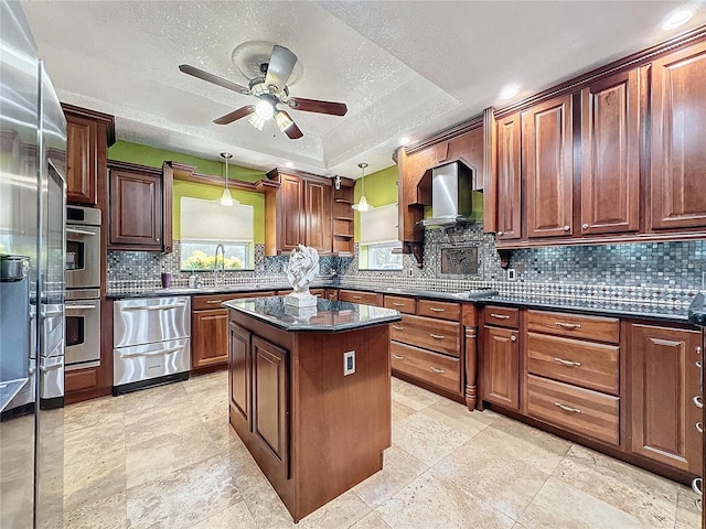 kitchen featuring double oven, a center island, ceiling fan, a raised ceiling, and tasteful backsplash