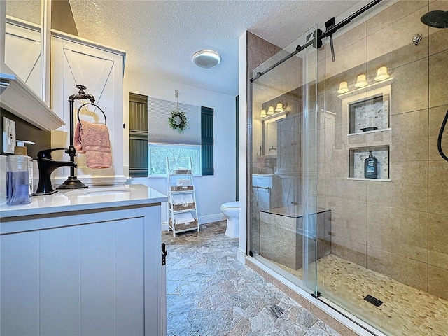 bathroom featuring a textured ceiling, vanity, an enclosed shower, and toilet