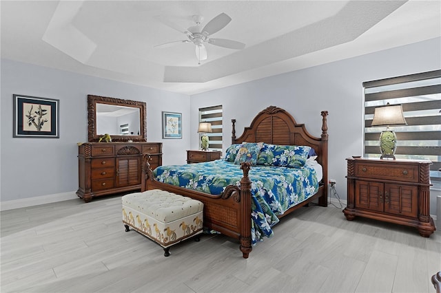 bedroom featuring light hardwood / wood-style floors, a raised ceiling, and ceiling fan