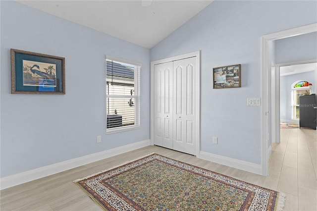 bedroom featuring light hardwood / wood-style floors, vaulted ceiling, and a closet