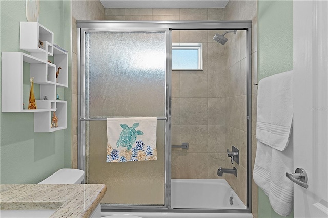 full bathroom with combined bath / shower with glass door, vanity, and toilet