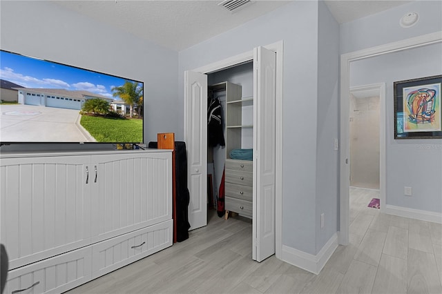 bedroom with a closet, a textured ceiling, and light wood-type flooring