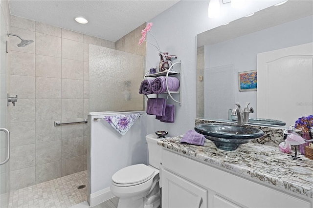 bathroom with a tile shower, vanity, a textured ceiling, and toilet