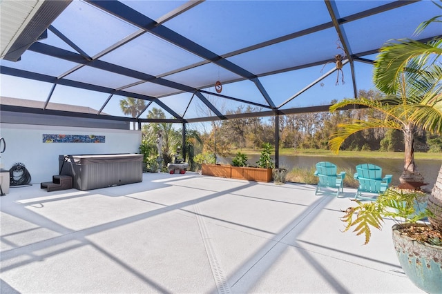 view of patio featuring glass enclosure, a water view, and a hot tub