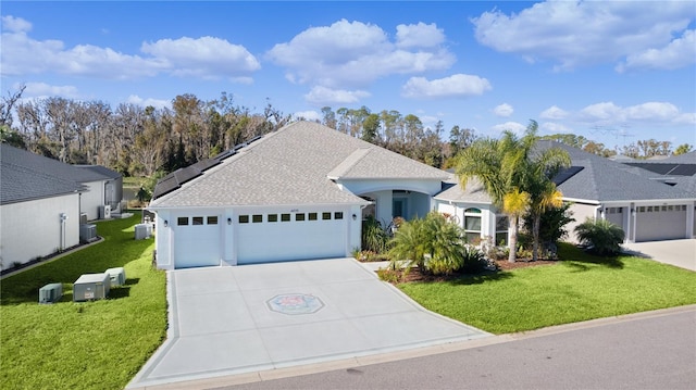 single story home with central air condition unit, a garage, a front yard, and solar panels